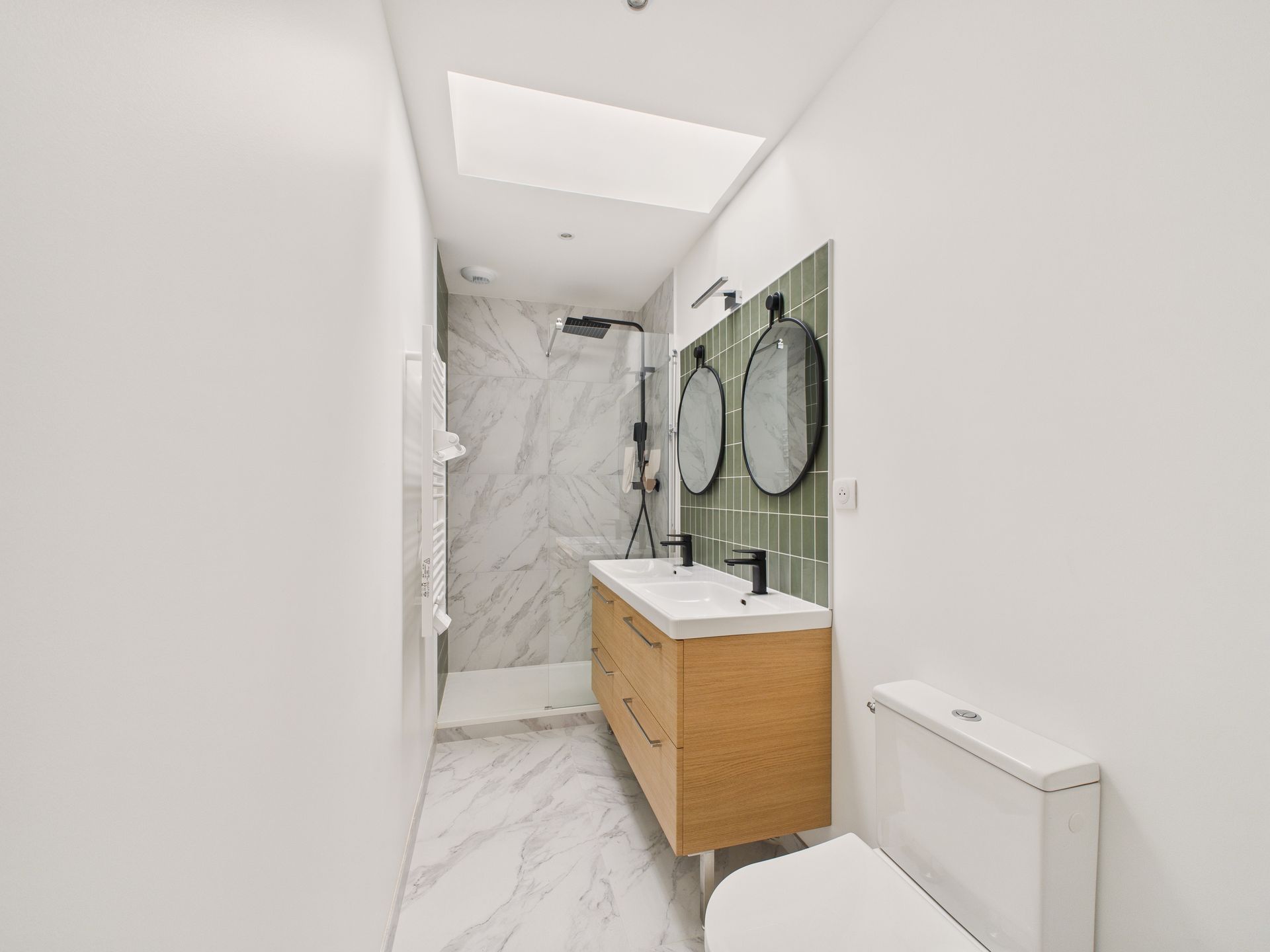 Salle de bain avec un meuble vasque en bois et deux miroirs ronds.