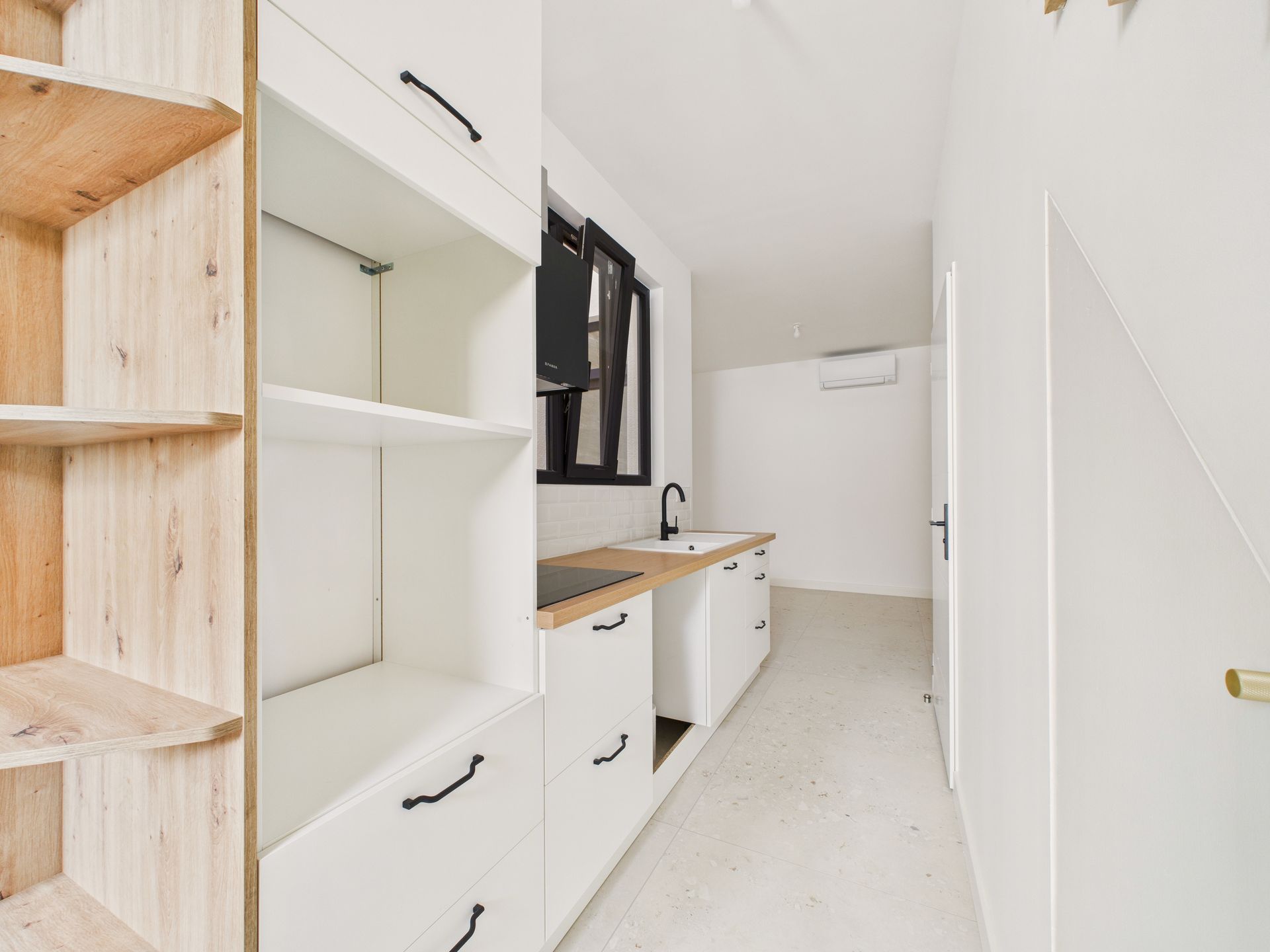 Cuisine blanche à plan de travail en bois, avec des étagères ouvertes.