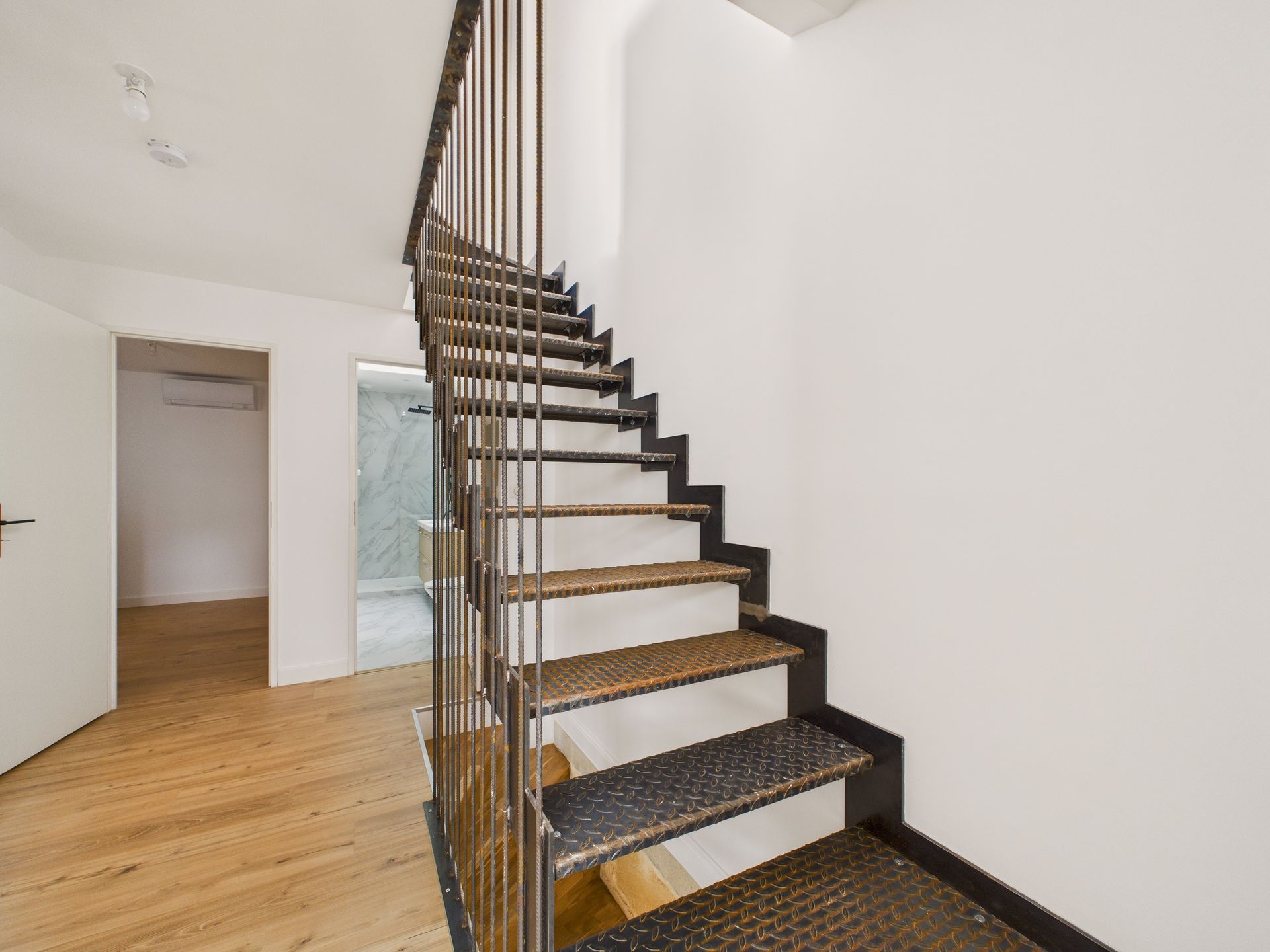Escalier métallique noir et mur blanc dans un intérieur rénové.