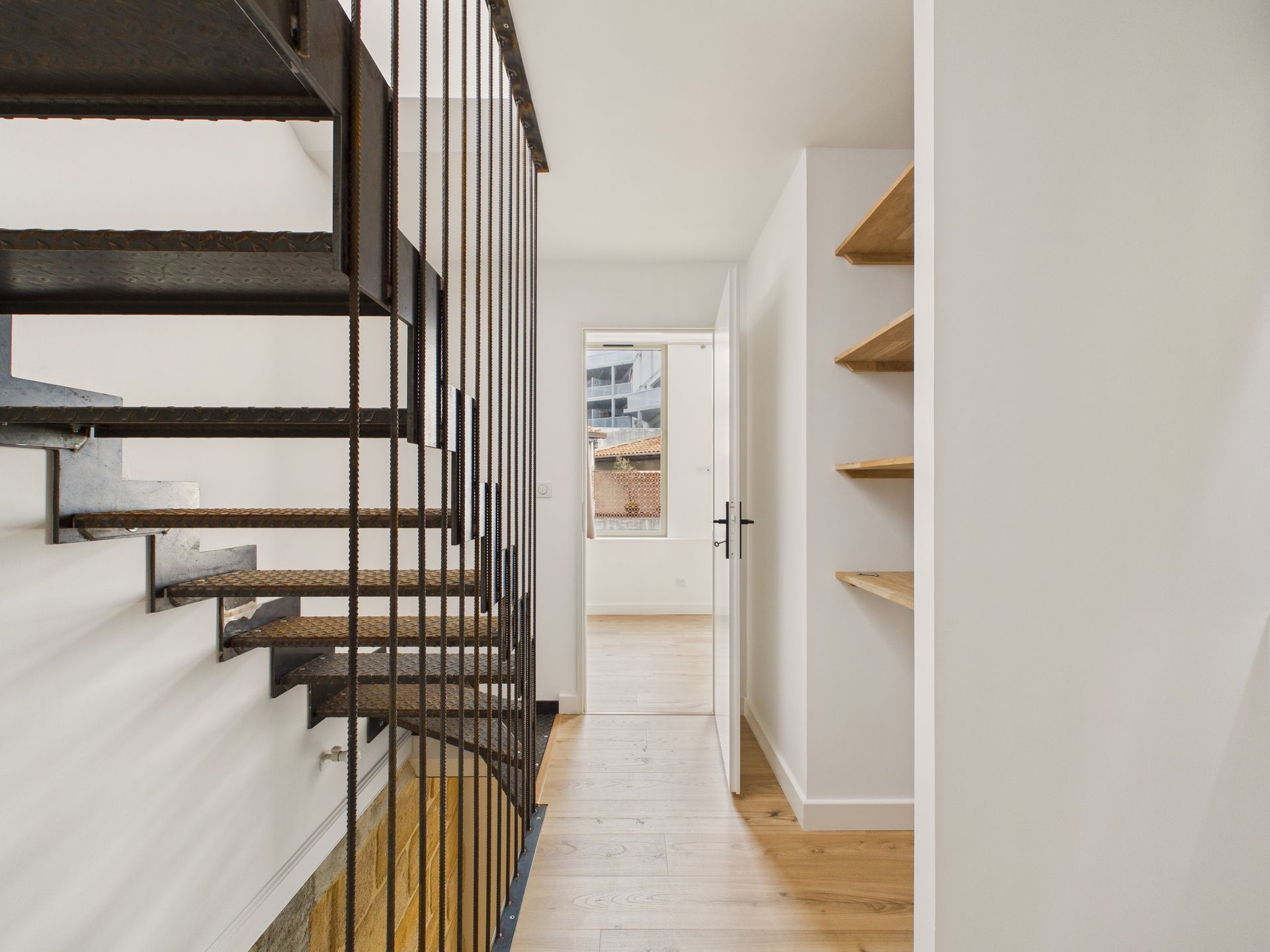 Détail des marches et du garde-corps noir d’un escalier intérieur.