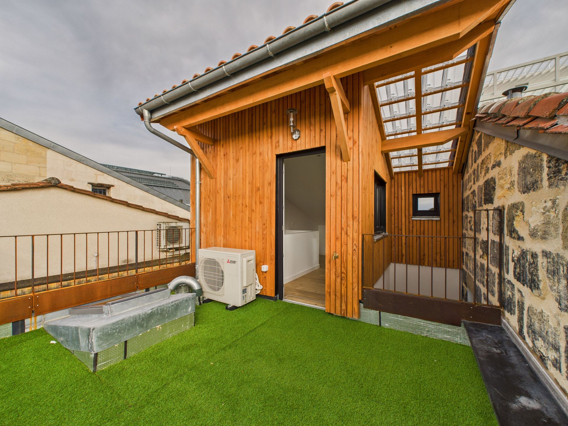 Terrasse extérieure avec un bardage en bois et une porte vitrée.