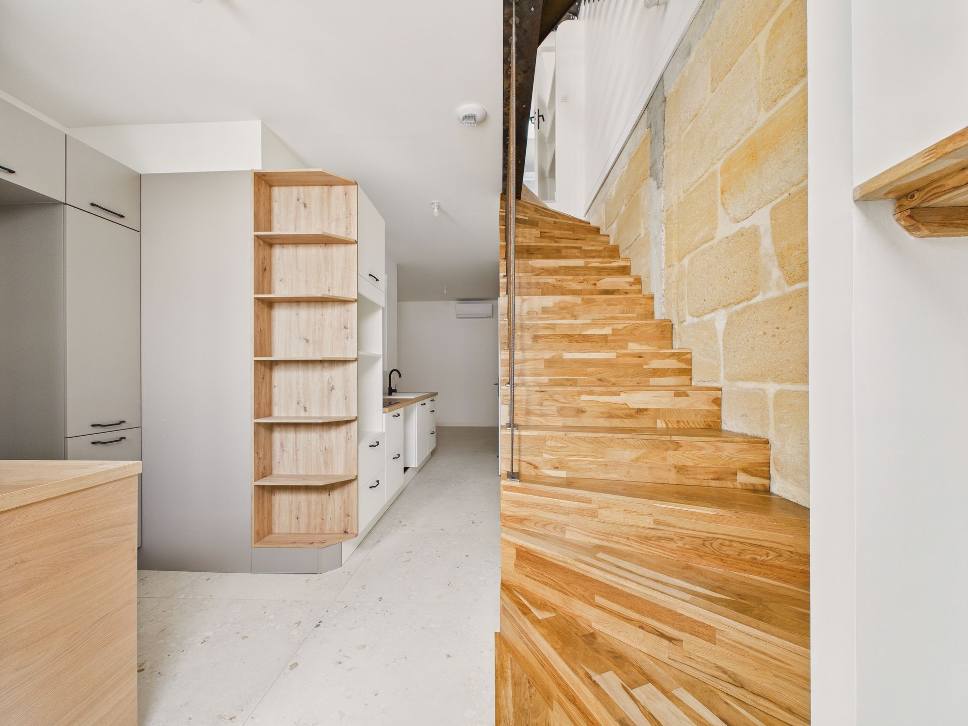 Escalier en bois à côté d’un rangement blanc et de niches ouvertes.