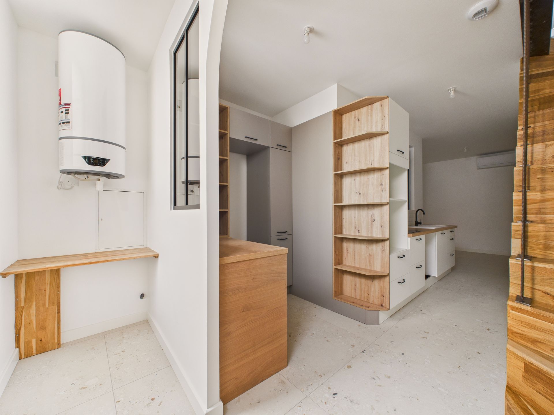 Entrée rénovée avec une cuisine blanche, un plan de travail en bois et un escalier.