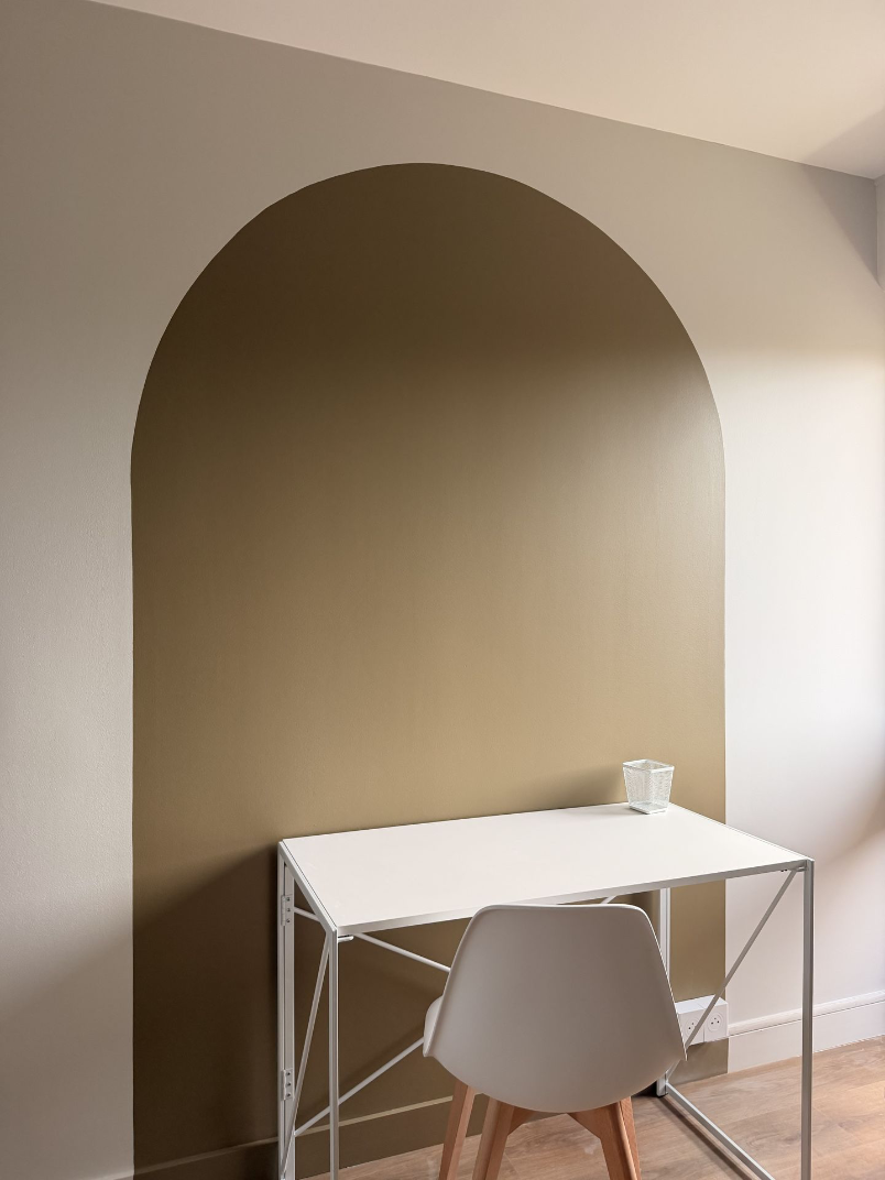 Bureau blanc installé dans une niche cintrée beige.