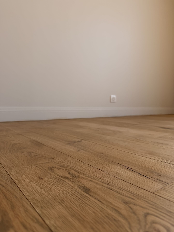Sol à effet bois et plinthes claires dans une pièce terminée.