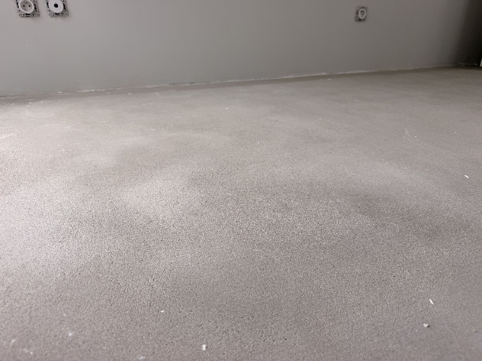 Surface de sol grise préparée dans une pièce en travaux.