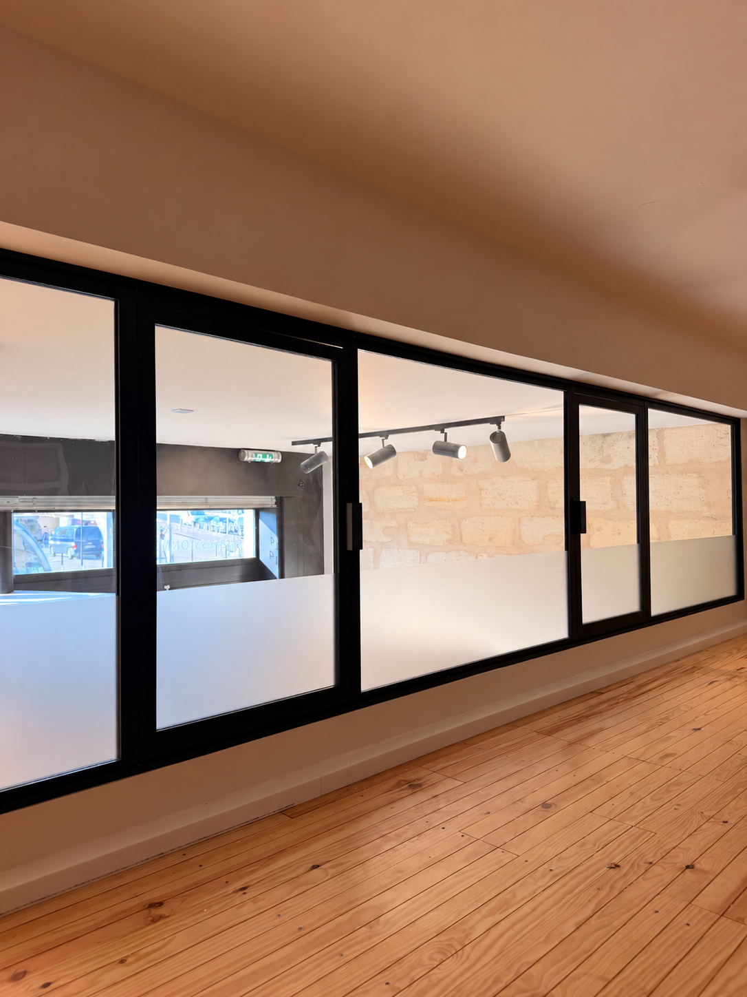 Bureaux séparés par une verrière noire, avec un plancher en bois.