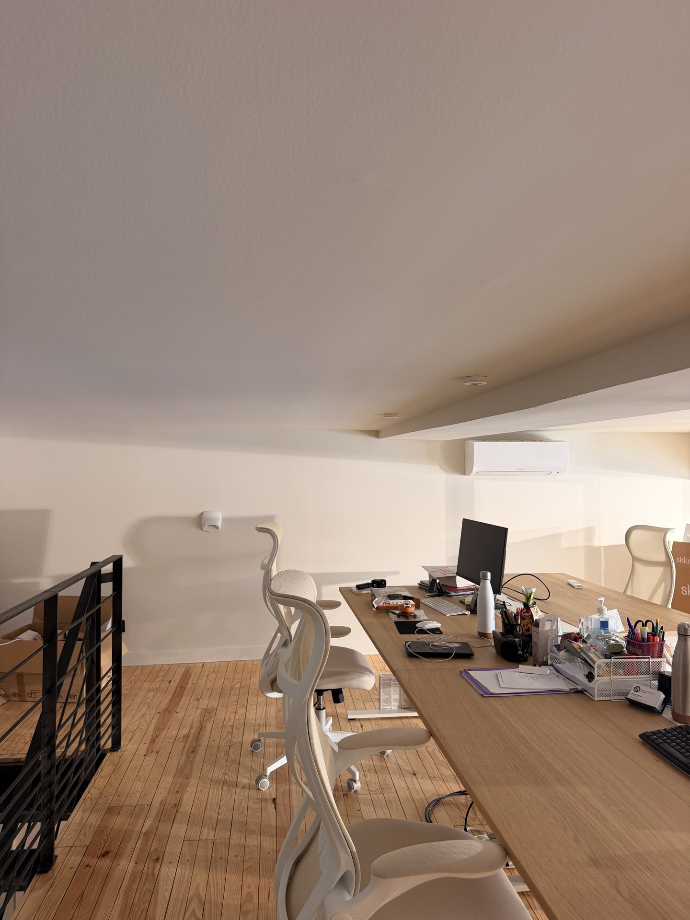 Espace de bureaux avec des postes de travail et un plancher en bois.