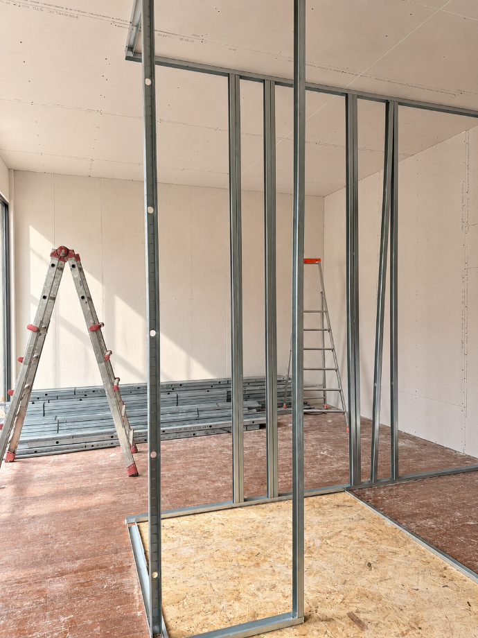 Ossature métallique d’une future cloison dans une pièce en travaux.