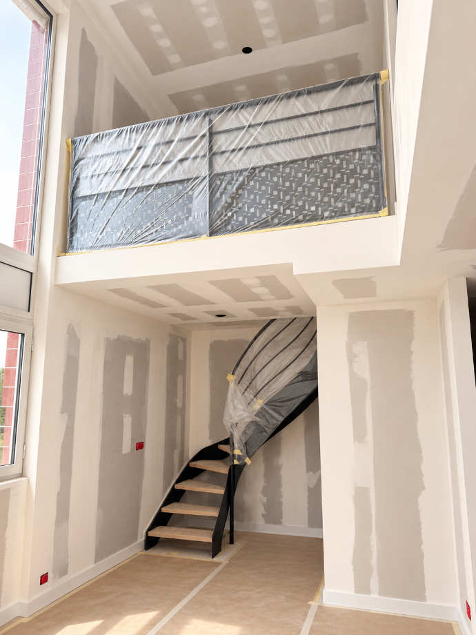 Cloisons et garde-corps en cours de réalisation autour d’un escalier intérieur.