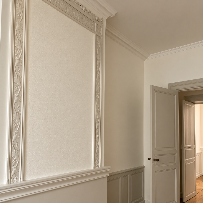 Mur et plafond blancs avec des moulures décoratives et une corniche.