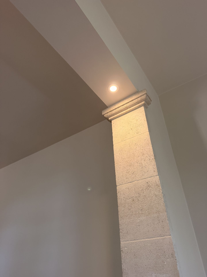 Pilier intérieur habillé et éclairé par un spot au plafond.
