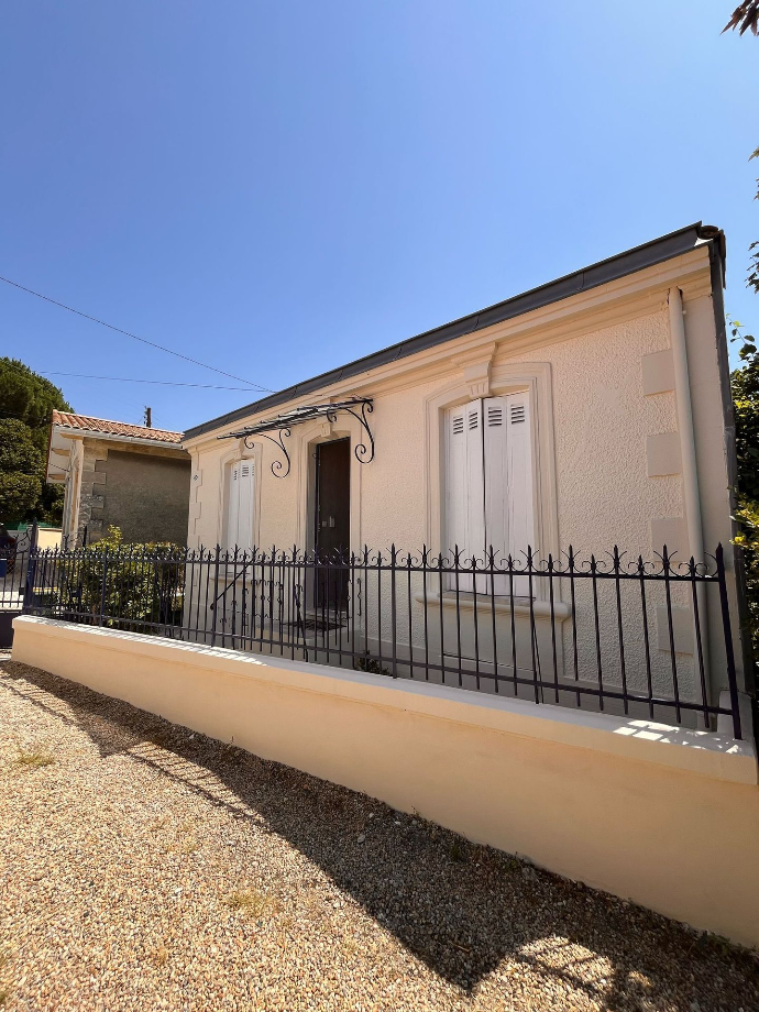 Façade d’une maison avec des fissures visibles et une clôture métallique.