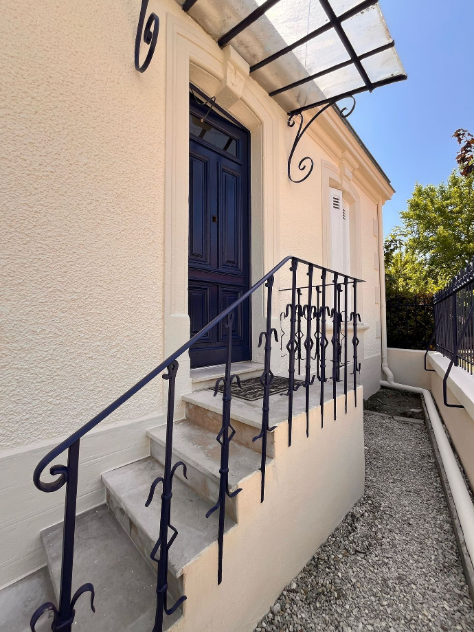 Escalier extérieur et façade claire avec une rambarde métallique noire.