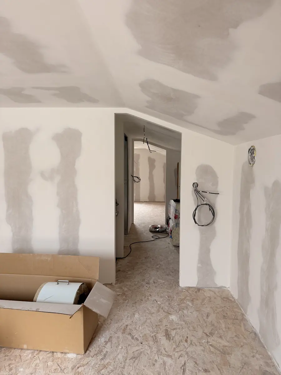 Couloir en plaques de plâtre avec des bandes de joints et des câbles en attente.