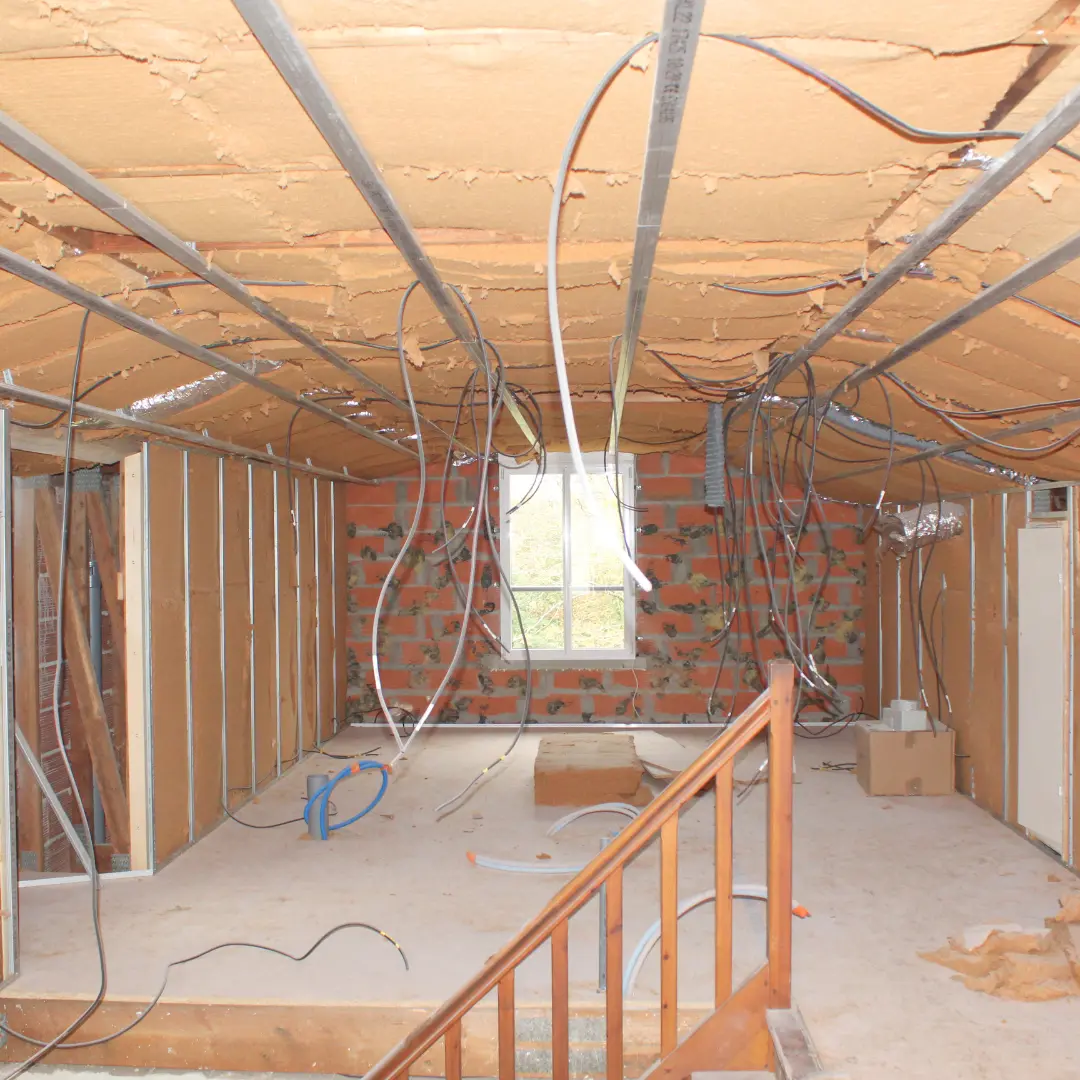 Étage en travaux avec un garde-corps, une ossature et de l’isolant au plafond.