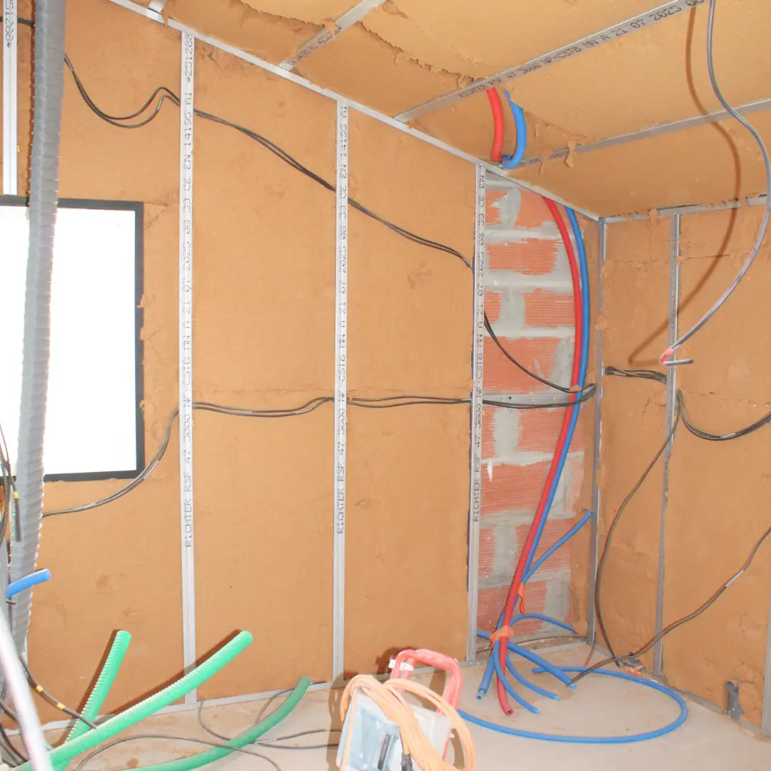 Réseaux électriques et ossature métallique devant un isolant mural.