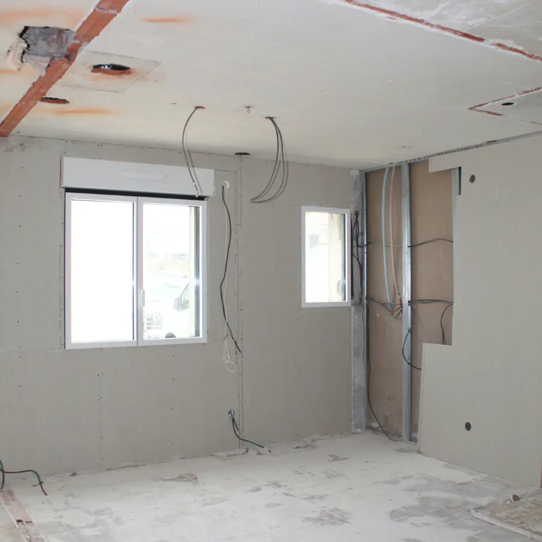 Pièce en cours de doublage avec une fenêtre et des câbles au plafond.