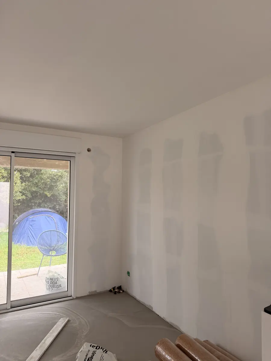 Pièce en travaux avec une porte-fenêtre et des joints de plaques apparents.