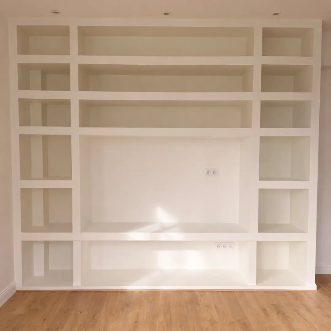 Bibliothèque blanche encastrée avec de nombreuses niches rectangulaires.