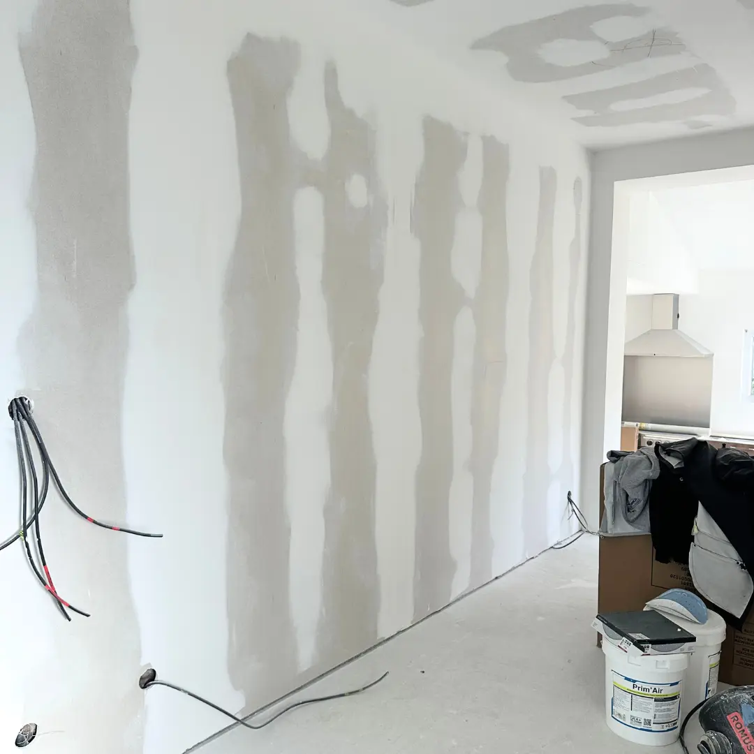 Mur jointoyé avec des câbles électriques et du matériel au sol.