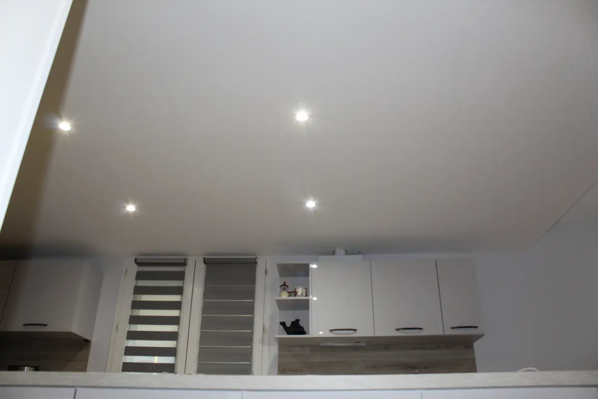 Cuisine blanche avec des spots encastrés dans le plafond.