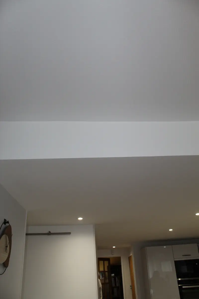 Retombée de plafond blanche au-dessus d’une pièce de vie.