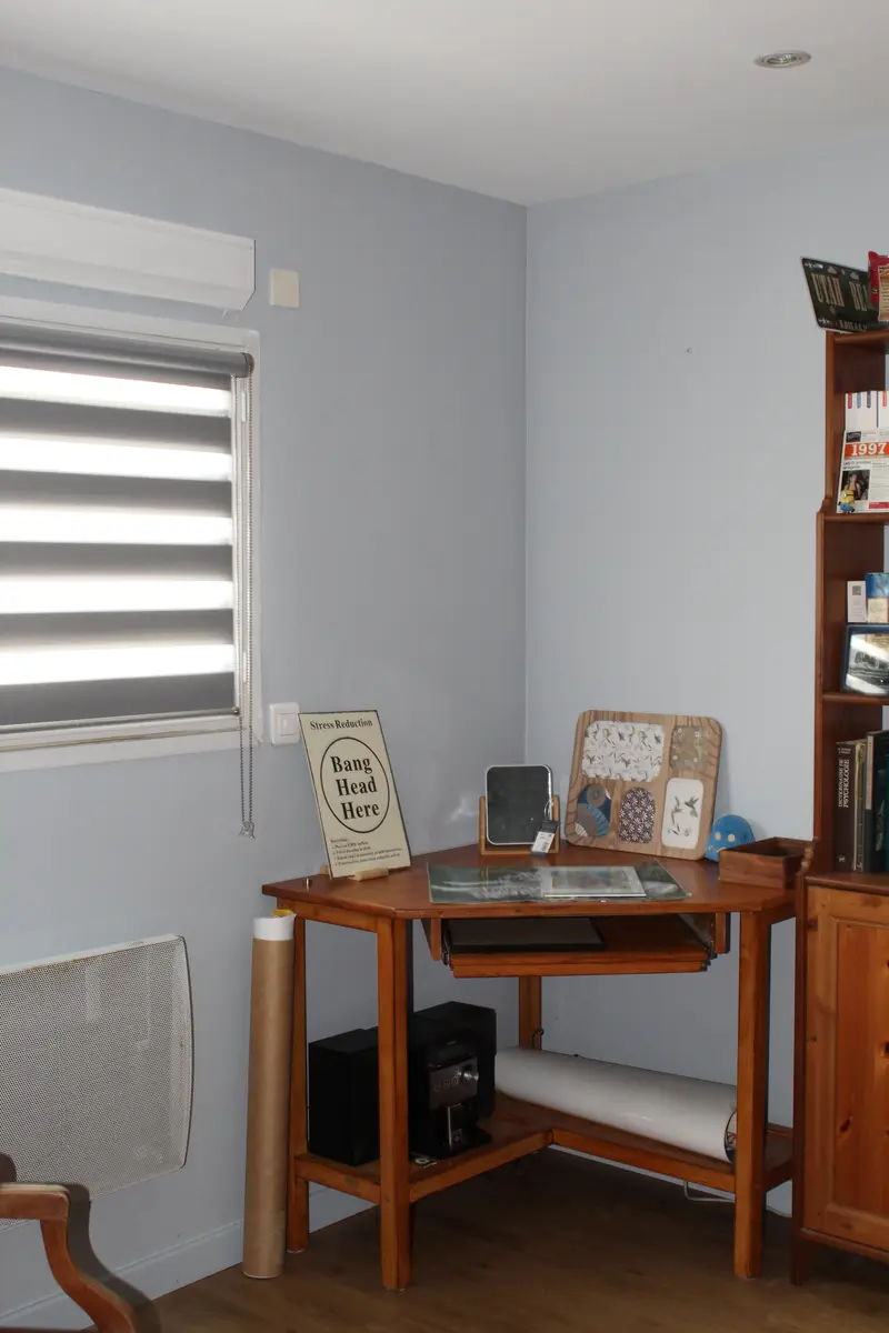 Coin bureau avec un mur gris clair, une fenêtre et un radiateur.