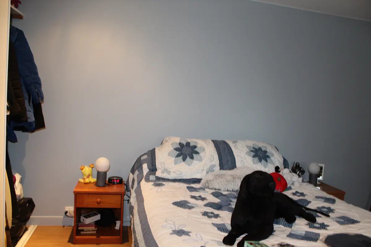 Chambre meublée avec un mur gris bleuté derrière le lit.