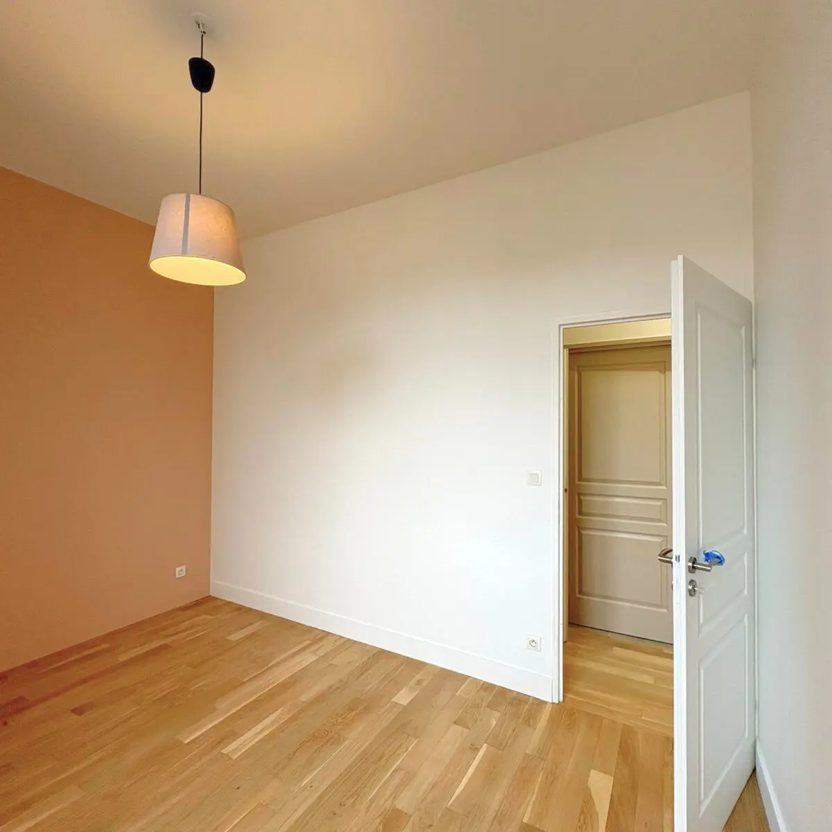 Pièce terminée avec un mur coloré, une suspension et un plancher en bois.