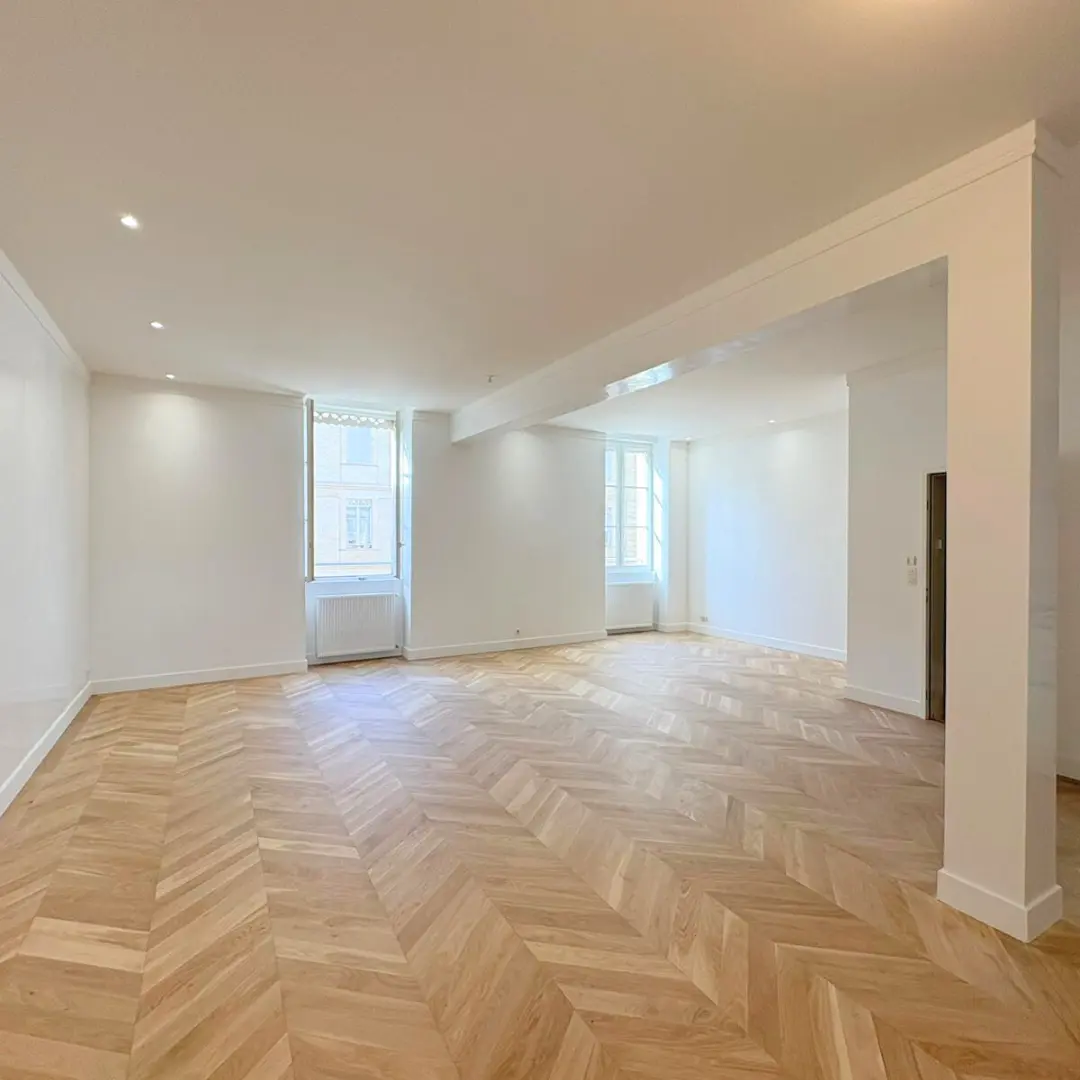 Grand séjour blanc avec une verrière et un sol en chevrons.
