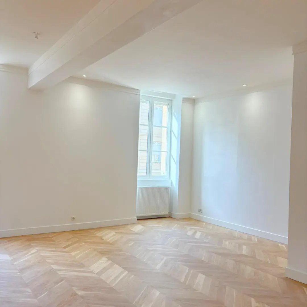 Murs blancs et plancher en chevrons autour d’une fenêtre.