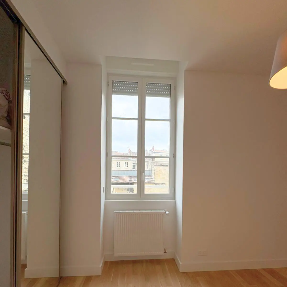 Fenêtre haute et radiateur dans une pièce aux murs clairs.