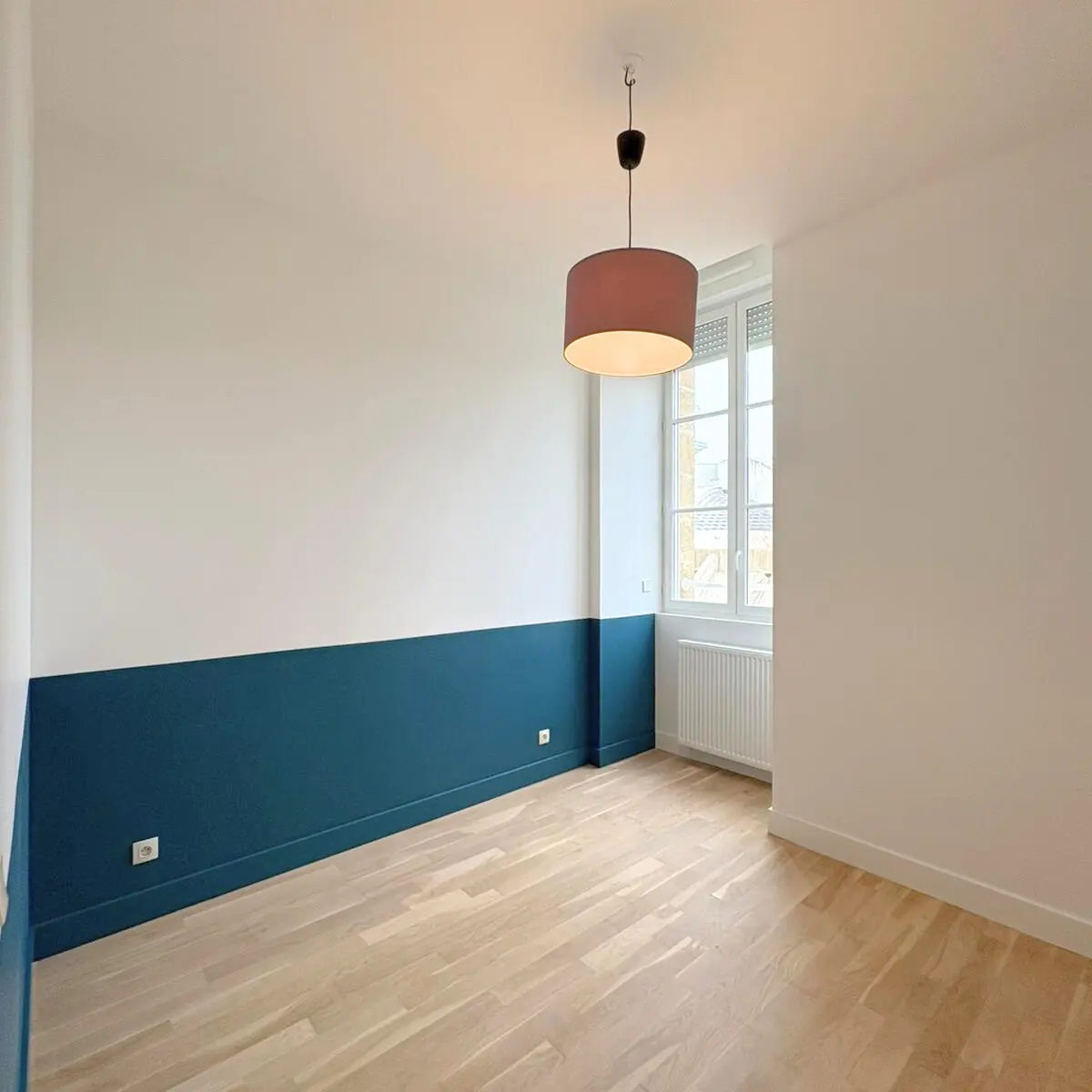 Pièce avec un soubassement bleu et un plancher en bois clair.