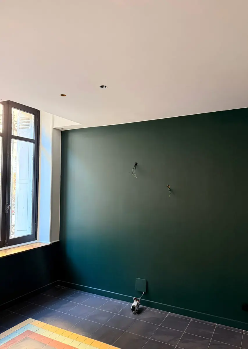 Mur vert foncé et plafond clair dans une pièce en finition.
