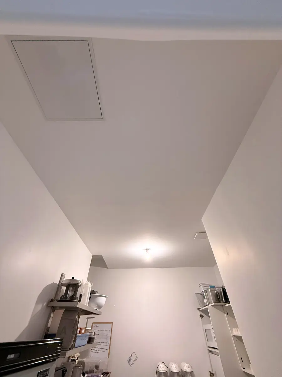 Plafond blanc à spots dans un espace de travail avec des étagères.