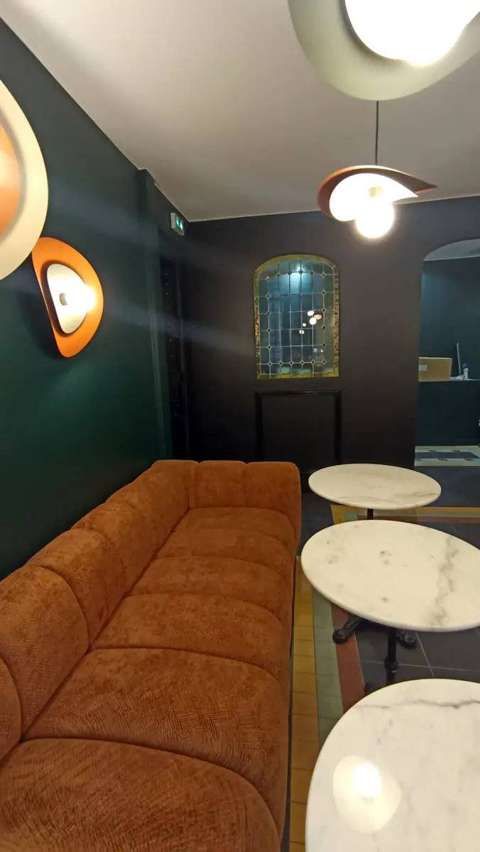 Banquette ocre et tables rondes contre des murs vert foncé.
