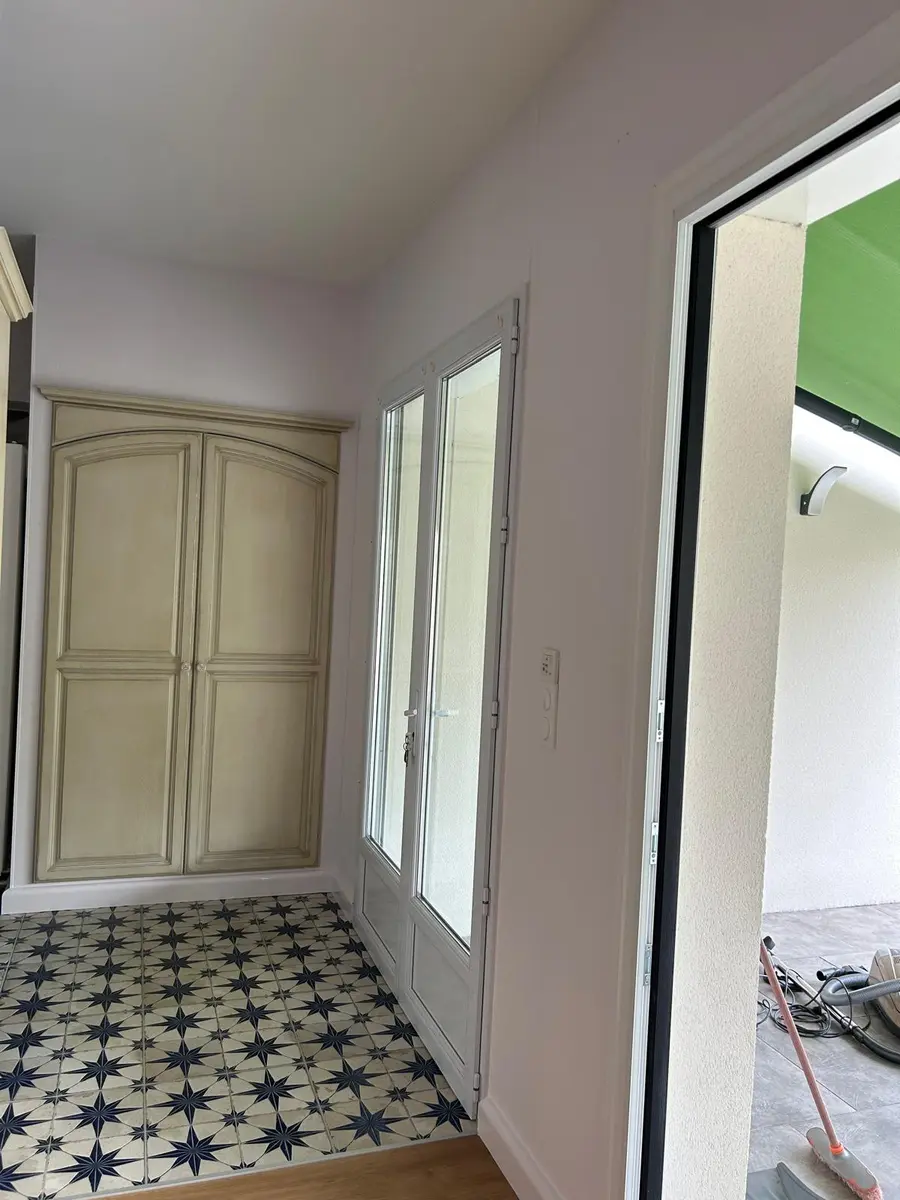 Passage entre deux pièces avec des portes claires et un sol à motifs.