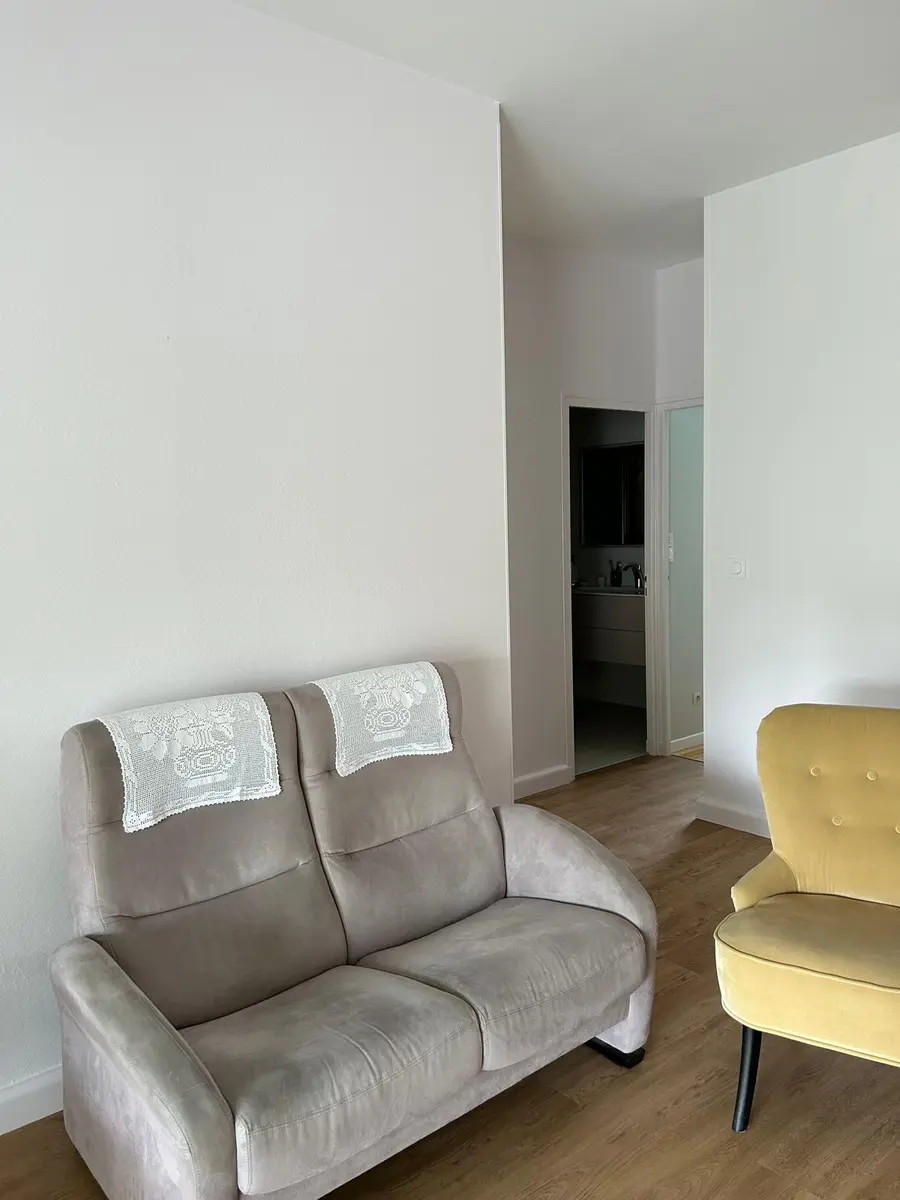 Coin salon avec des fauteuils et des murs blancs.