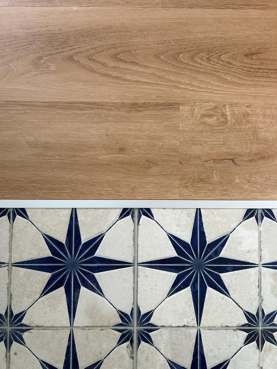 Jonction entre un revêtement à effet bois et un carrelage à motifs étoilés.