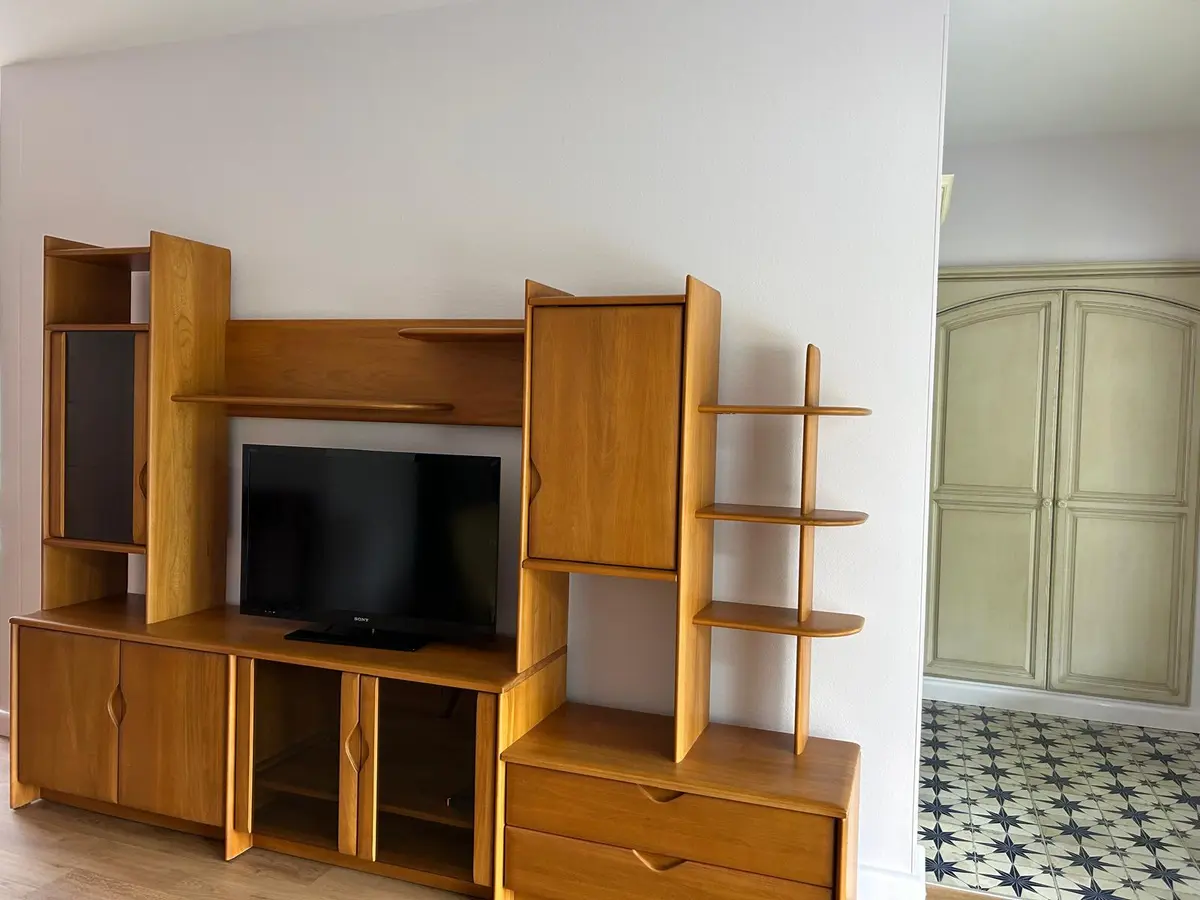 Meuble de télévision en bois placé contre un mur blanc.