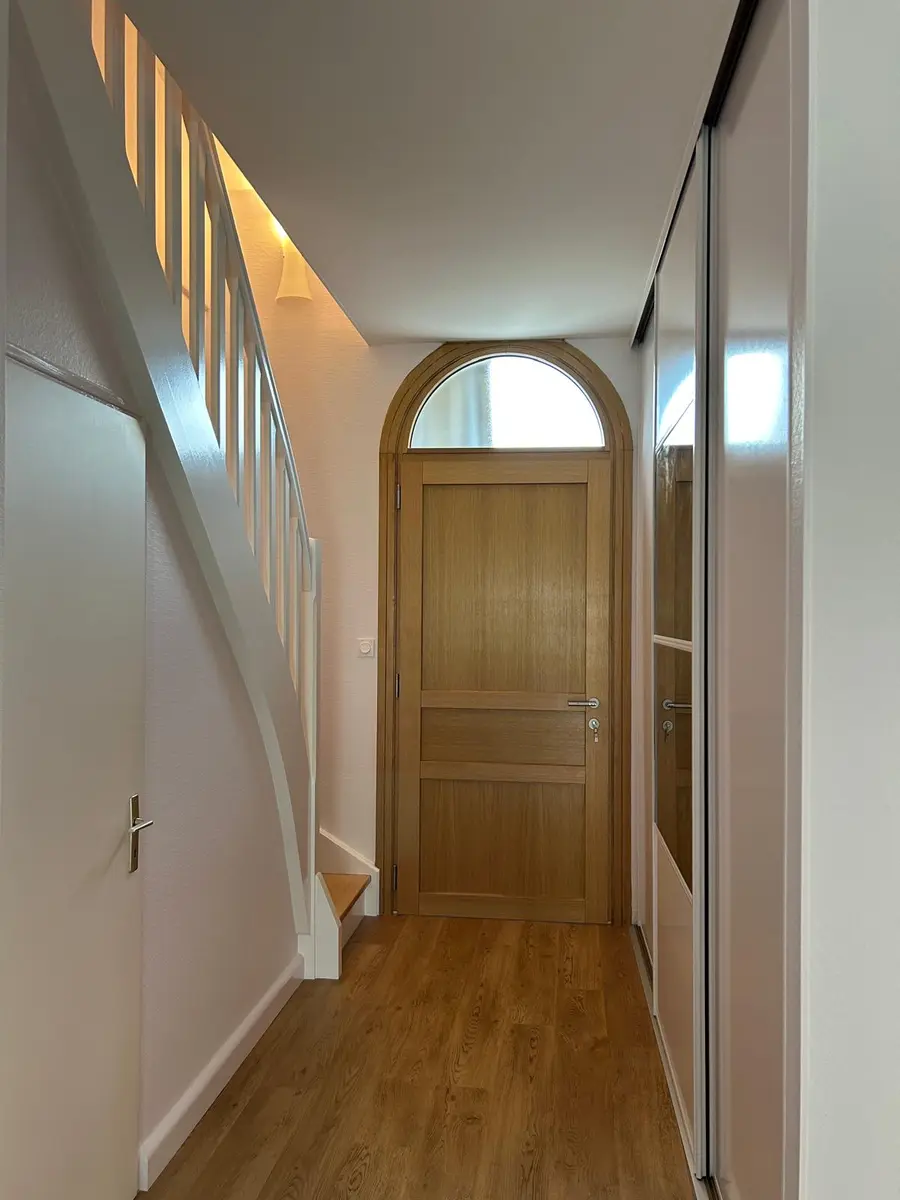 Couloir rénové avec un escalier, une porte en bois et un sol à effet bois.