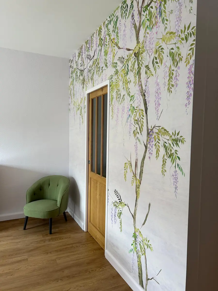 Papier peint végétal près d’une porte en bois et d’un fauteuil vert.