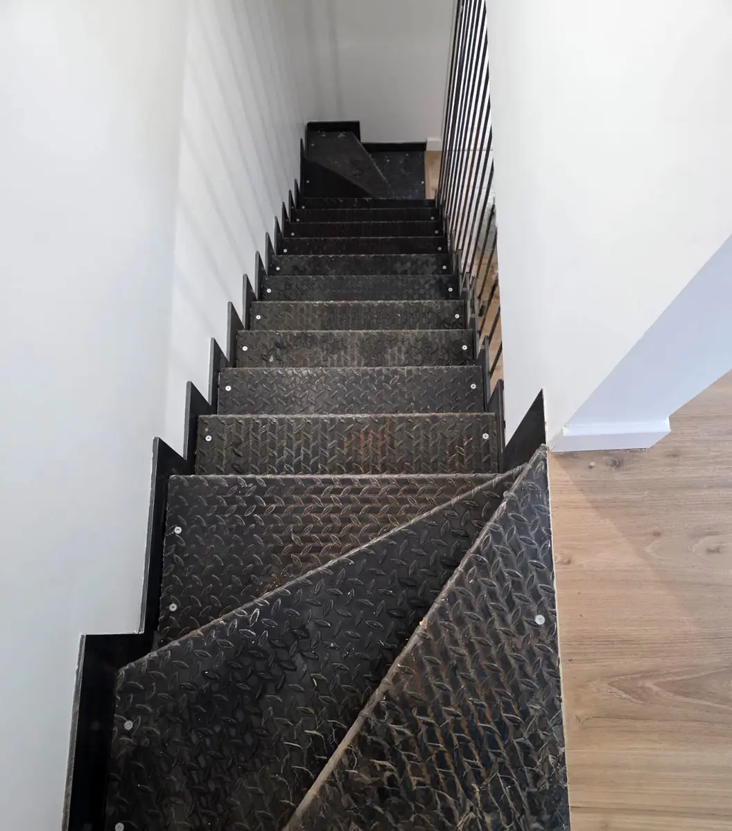 Escalier droit à marches foncées au-dessus d’un sol à effet bois.