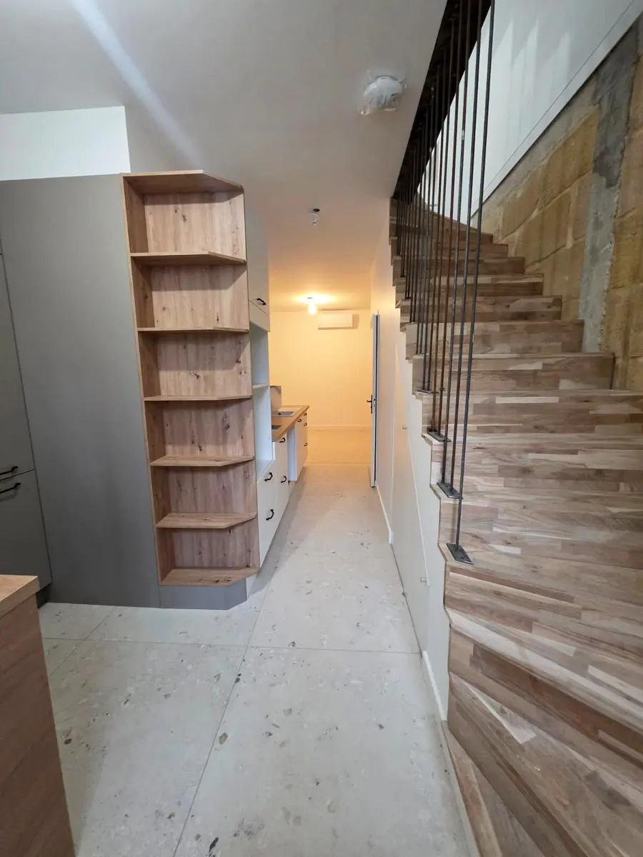 Bibliothèque arrondie et escalier intérieur dans un espace en cours de finition.