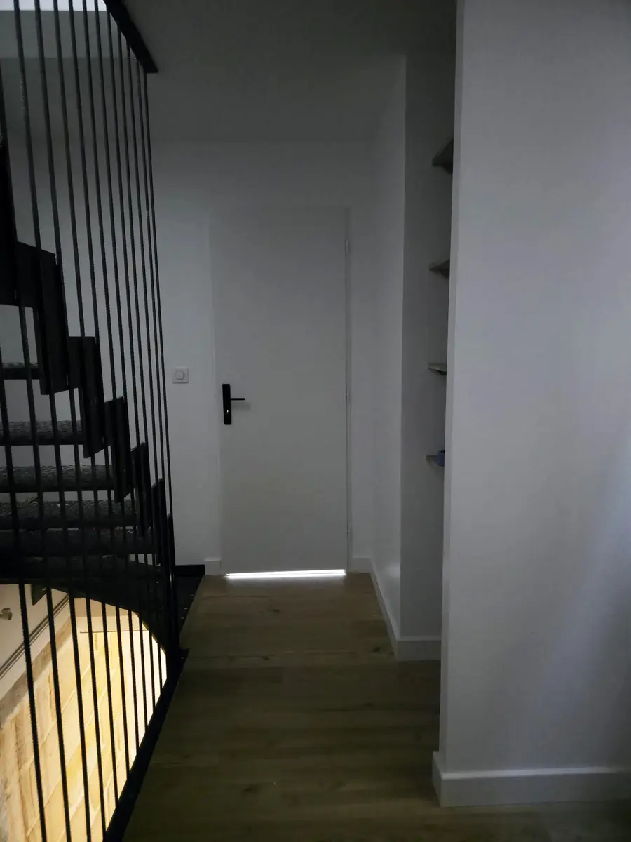 Palier avec un garde-corps noir et une porte blanche.
