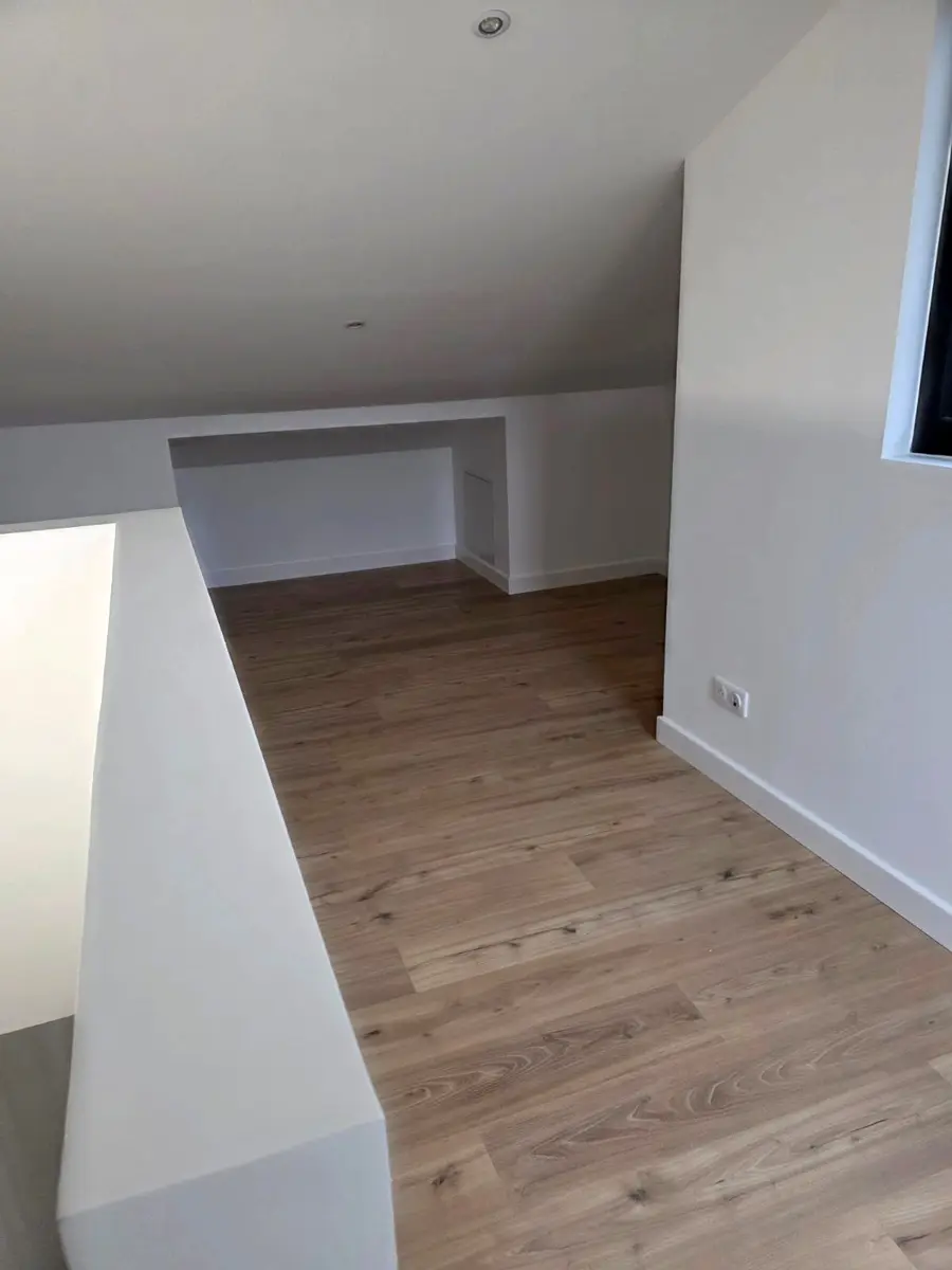 Pièce sous pente avec des murs clairs et un sol à effet bois.