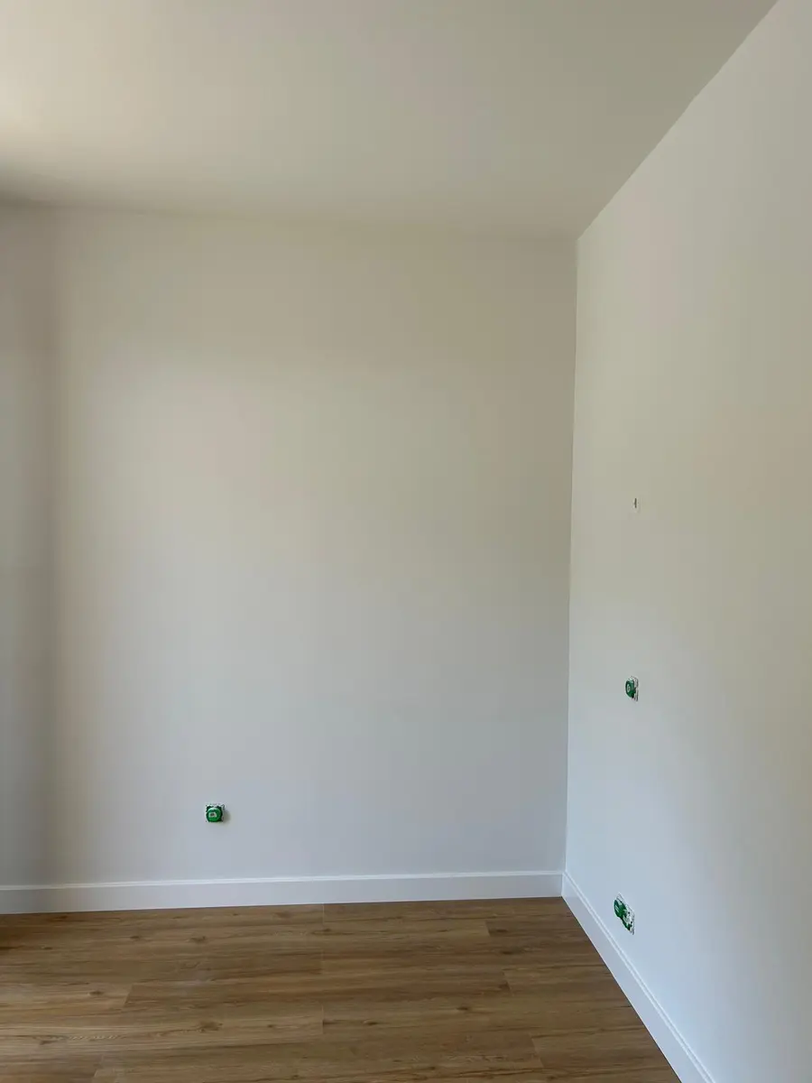 Angle de pièce aux murs clairs avec un sol à effet bois.