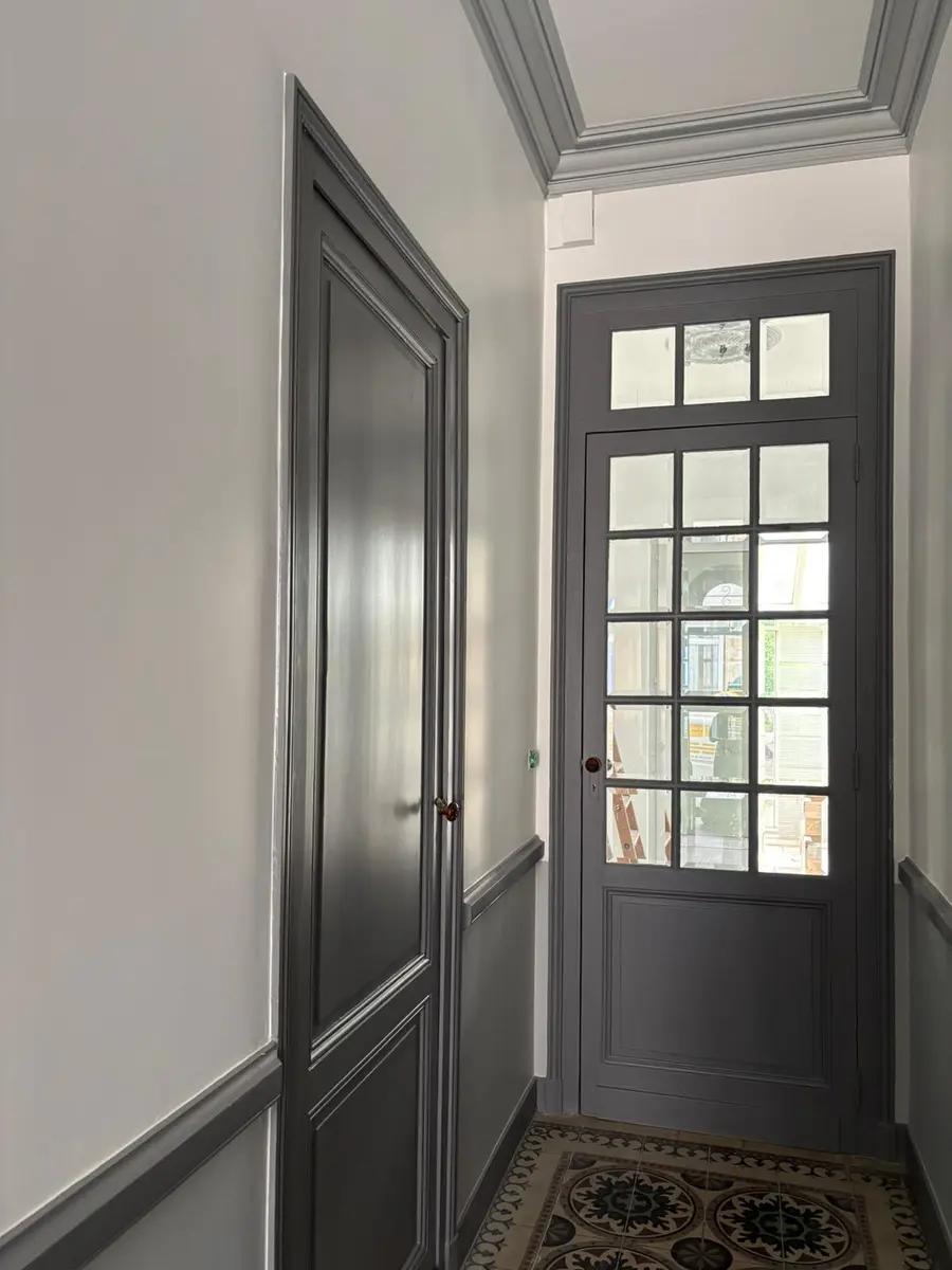Porte vitrée et encadrements peints en gris dans un couloir.