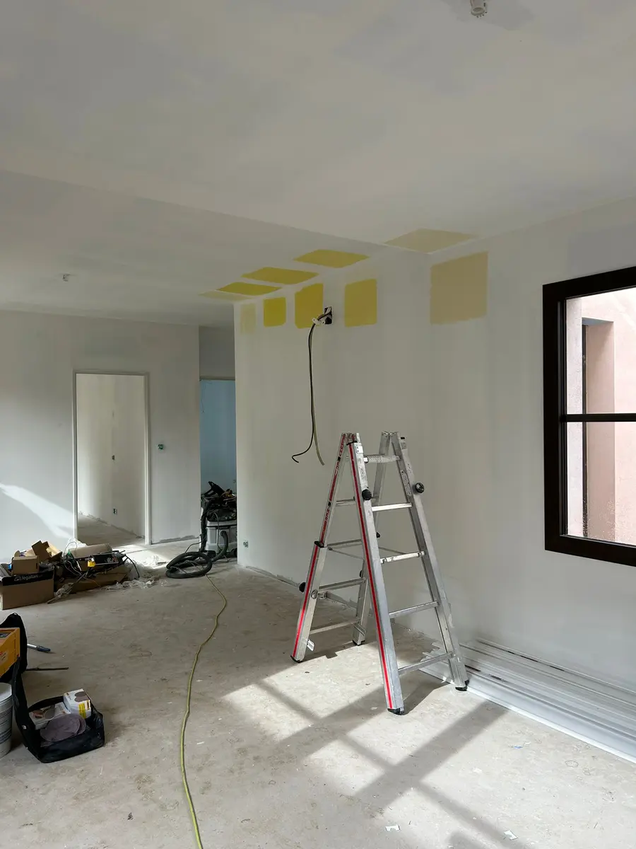 Pièce avant finition, avec des traces de préparation sur les murs et un escabeau.
